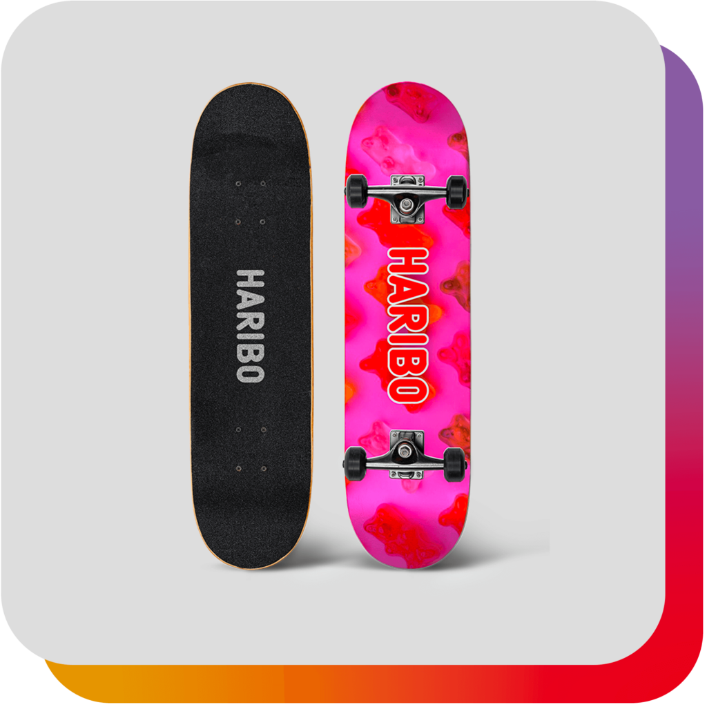 Fiche produit : Finger skate Haribo aux couleurs roses avec motif de petits oursons en gélatine, sur fond gris clair, avec signature arc-en-ciel en arrière-plan.