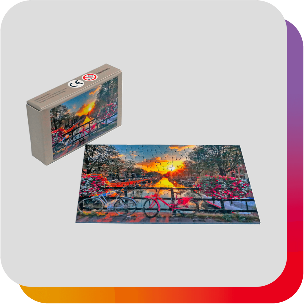 Fiche produit : Mini puzzle avec image de deux vélos sur un pont fleuri au coucher du soleil, sur fond gris clair avec signature arc-en-ciel en arrière-plan.