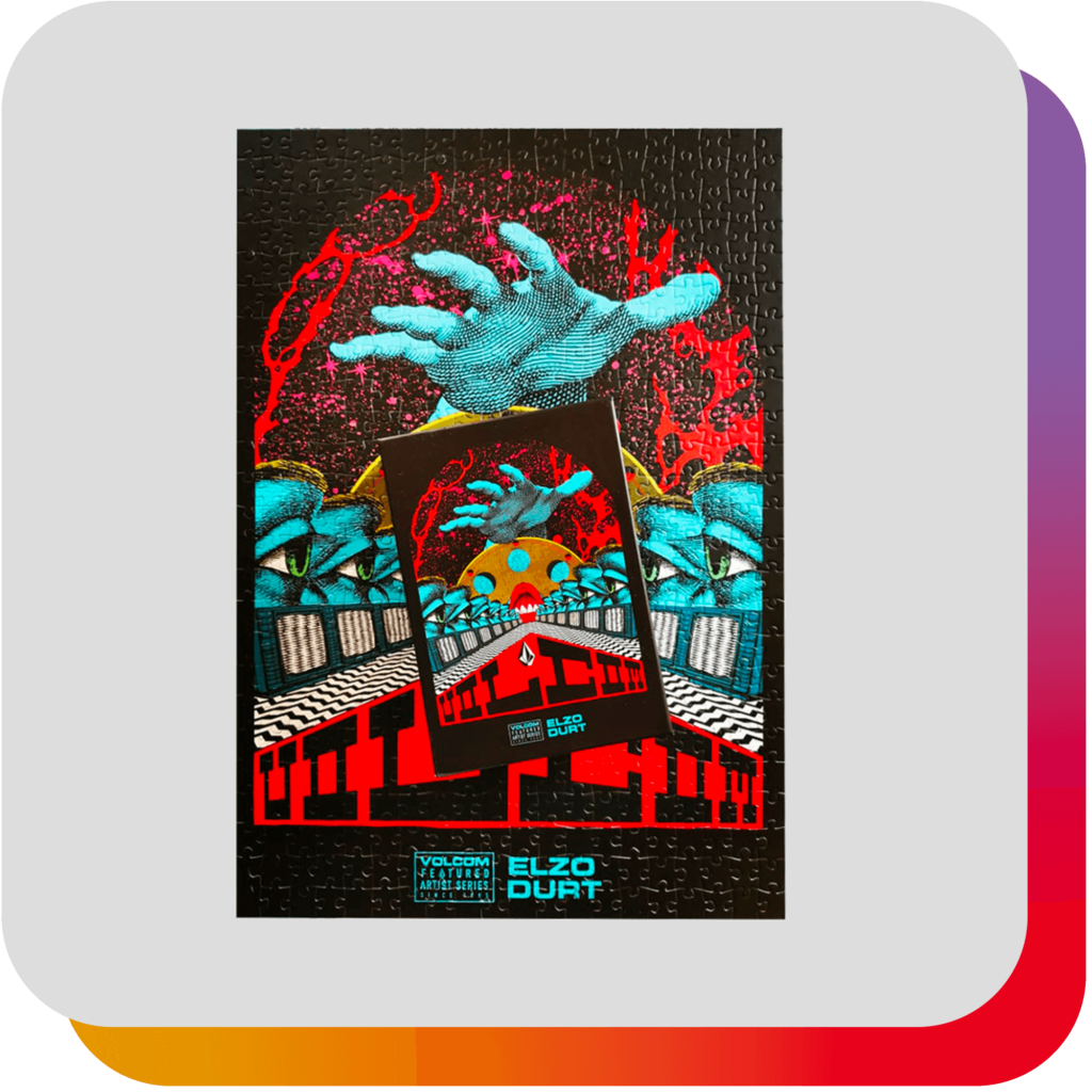 Fiche produit : Mini puzzle Volcom 99 pièces avec illustration artistique dominée par les couleurs noir, rouge et bleu turquoise, sur fond gris clair avec signature arc-en-ciel en arrière-plan.